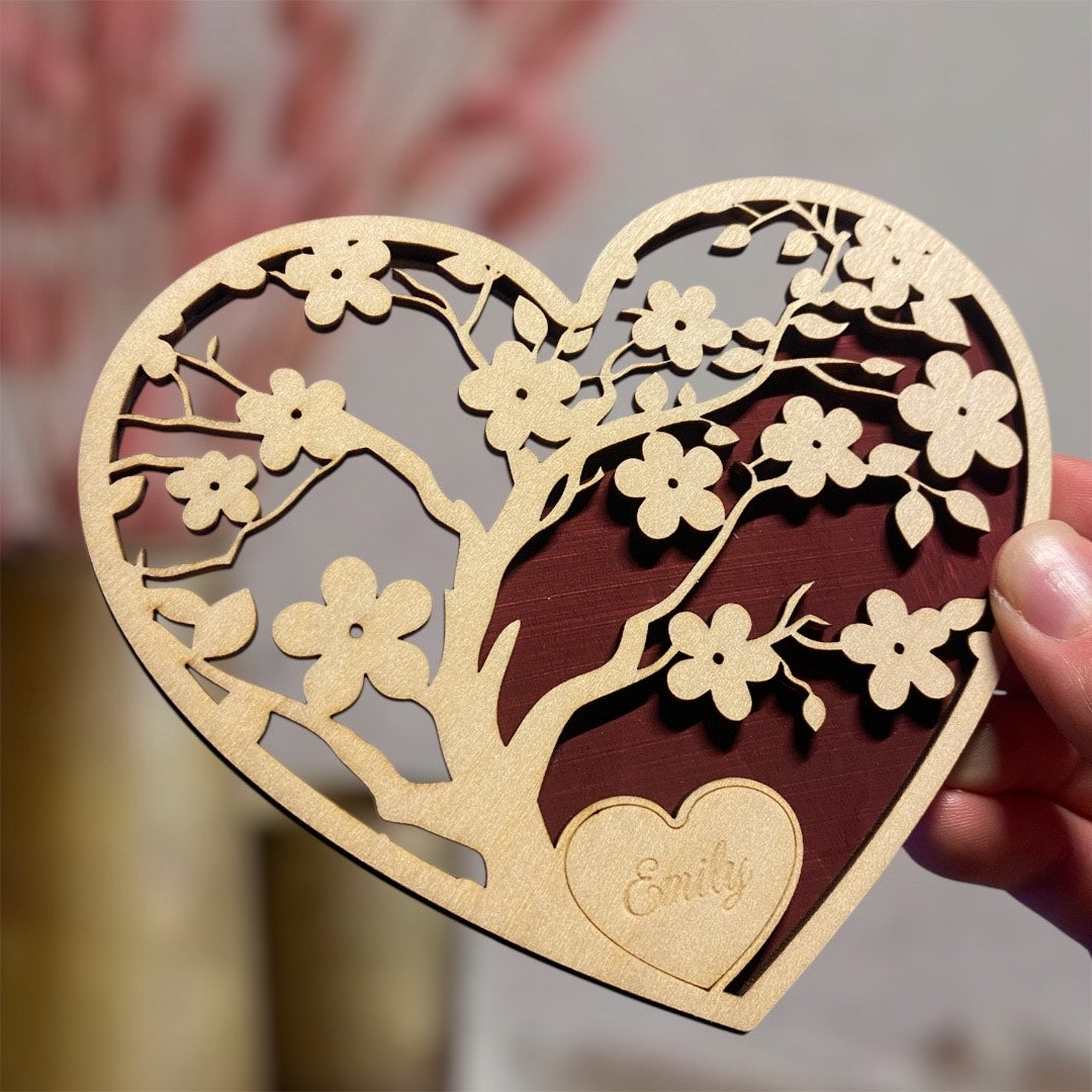 right hand holding wooden heart with cherry blossom cutouts on red background